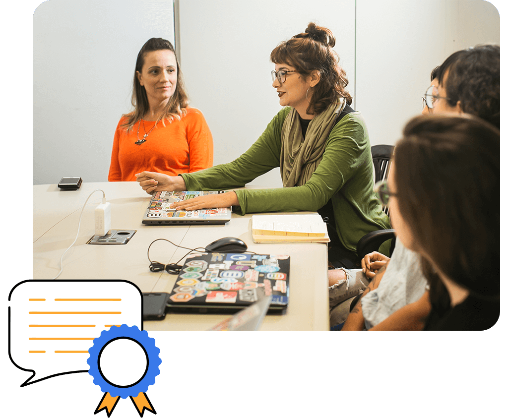 Cuatro personas en una reunión de marketing alrededor de una mesa con computadoras y cuadernos